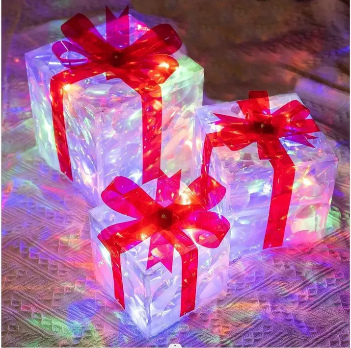 Three LED light-up gift boxes with red bows on a textured surface.